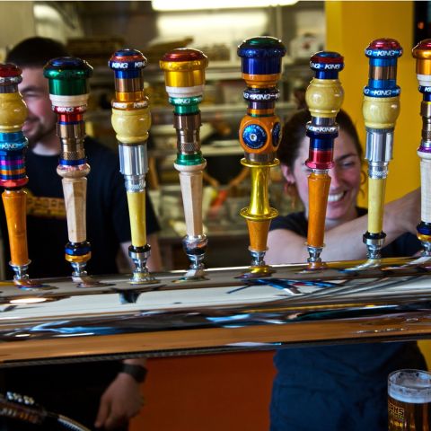 bartenders pouring beer from a line of beer taps at Hopworks Brewery