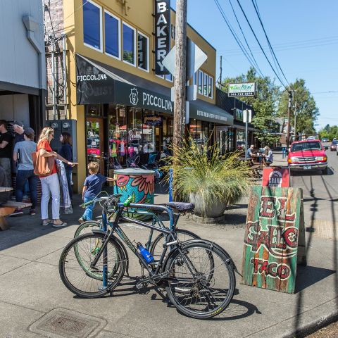 People dining at an outdoor table on the sidewalk while others walk by in the Woodstock neighborhood