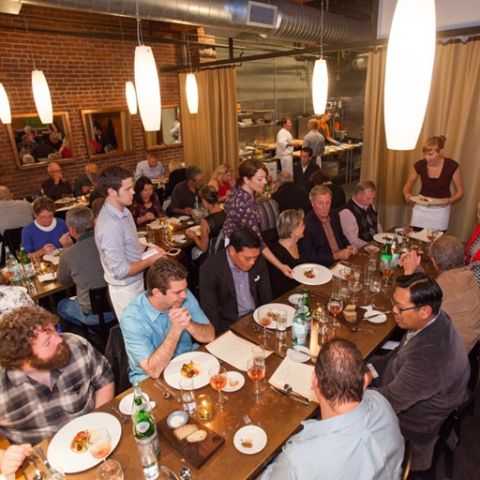 diners seated at long tables being served dishes