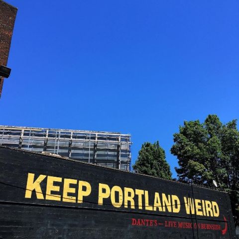 \"Keep Portland Weird\" painted in yellow on a black brick wall