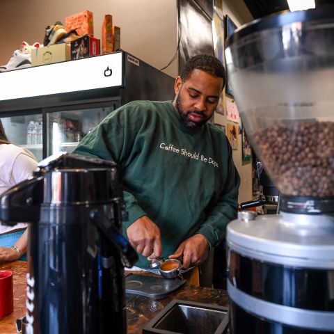 man and woman behind counter preparing espresso at a coffee shop