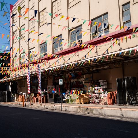 sun on large warehouse with colorful flags and outdoor racks for shopping