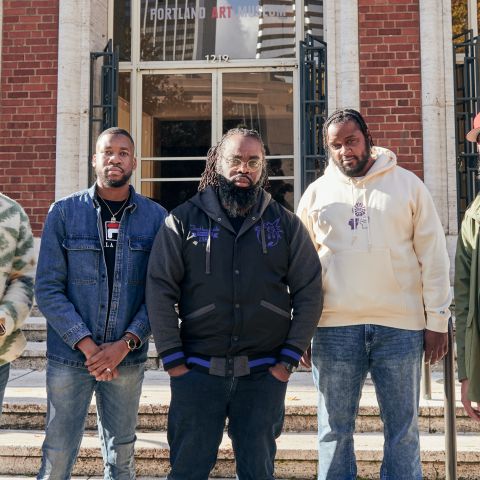 Five men stand in front of a set of marble steps leading up to a brick building