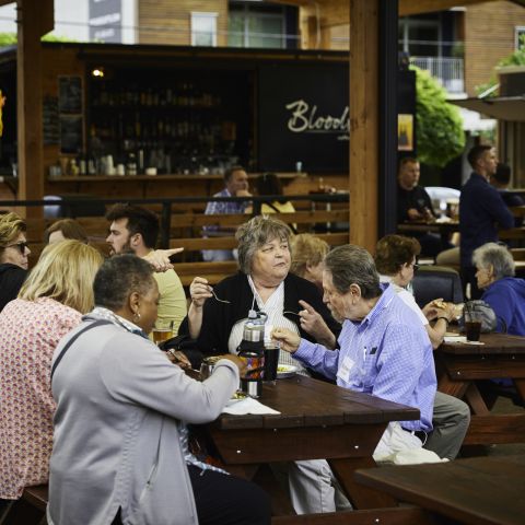 people eating at picnic tables in busy food cart pod