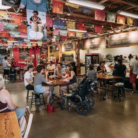 groups of people at tables in an indoor market dining area