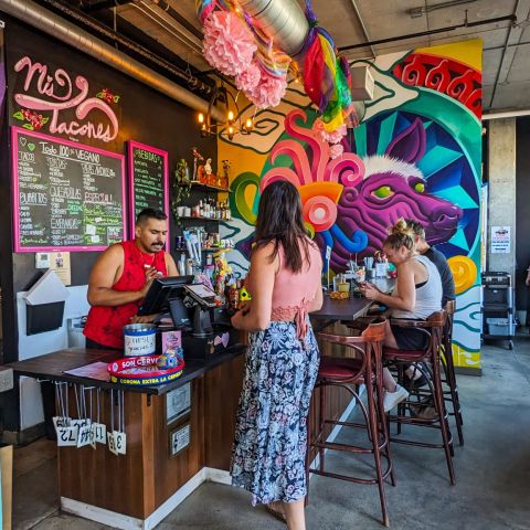 someone orders at a restaurant that is colorfully decorated, people fill the chairs in the background