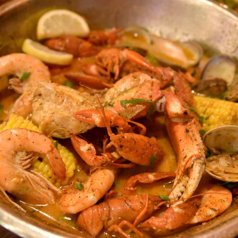 close up of crawfish dish with lemons, herbs, and broth