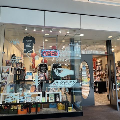 comic book store front showing shelves, books and t-shirts inside