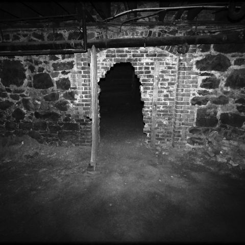 a black and white image of a crumbling doorway in a brick wall