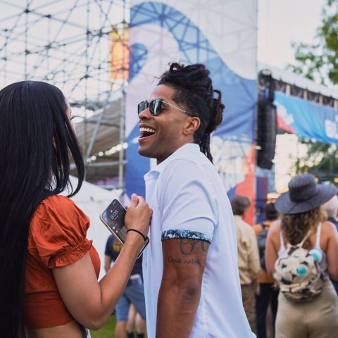 two people laughing with a crowd and stage in the background