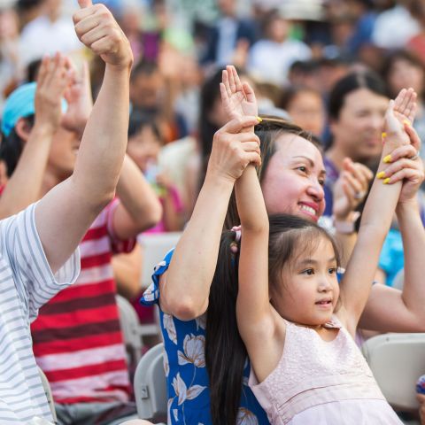 a family sitting in chairs raise their arms while watching a performance