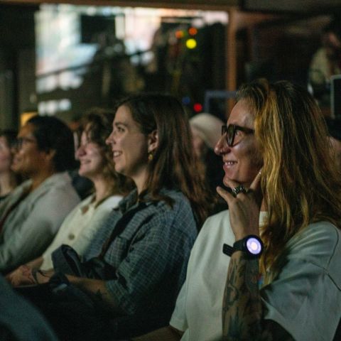 a close-up of a row of smiling people seated in a theater