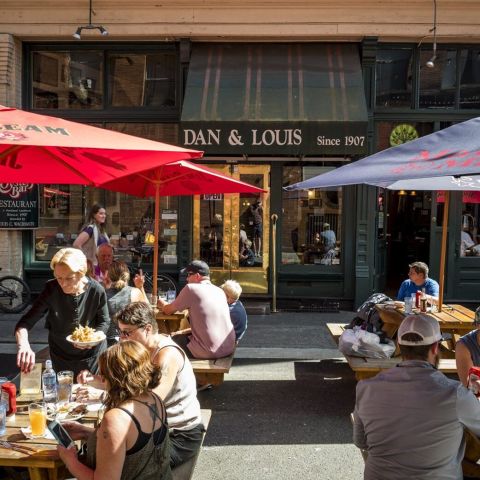 people eat and drink at picnic tables outside a restaurant