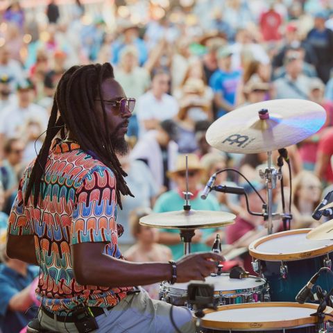 a person sitting at a drum kit in front of a crowd