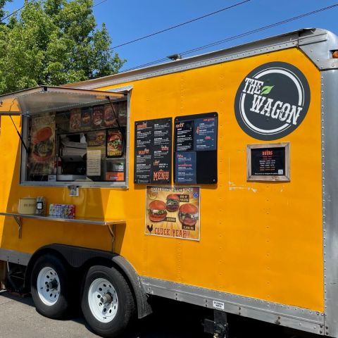 a bright yellow food cart advertising plant-based food with a circular sign reading “The Wagon”