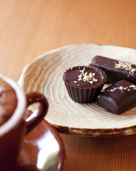 dish of truffle chocolates next to a mug of coffee on a wooden coffee table