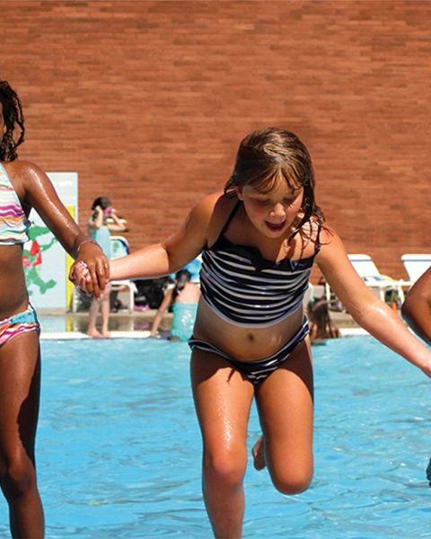 three children holding hands in a pool