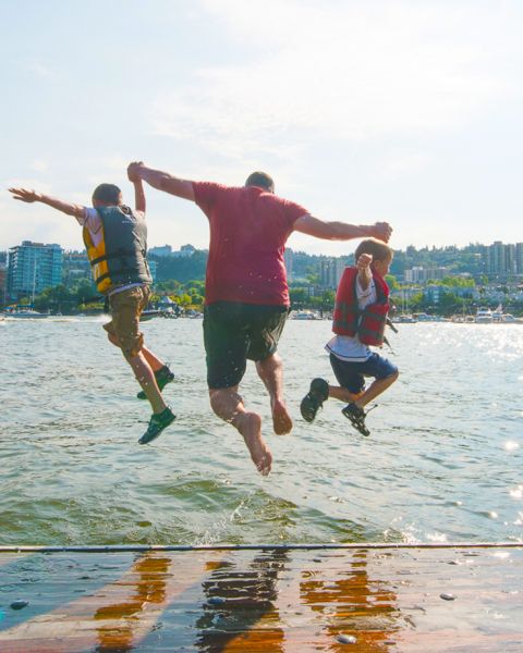 three people mid-jump into a river