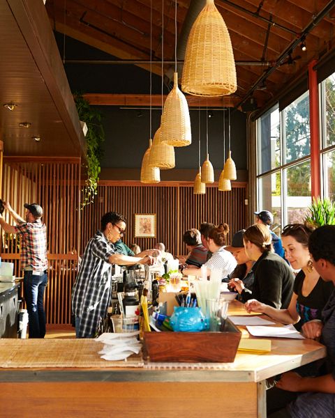 two bartenders make drinks while customers sit at the bar looking at menus