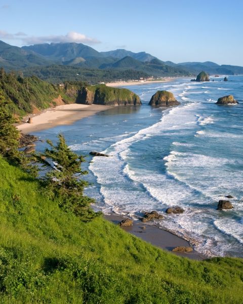 view overlooking Ecola Point, ocean waves crashing on the beach wit h large rock formations