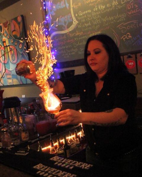 a bartender making a flaming drink behind the bar at Local Lounge