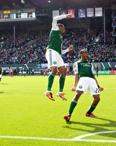 Two Portland Timbers soccer players celebrate on the field after a goal
