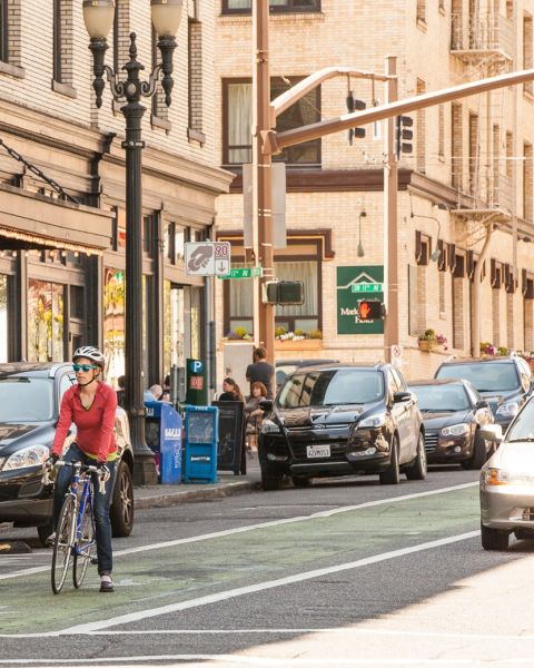 woman riding a bike in a green-painted bike-only lane in downtown