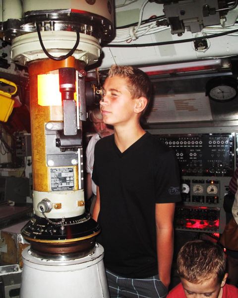 an adolescent boy looking through a submarine scope