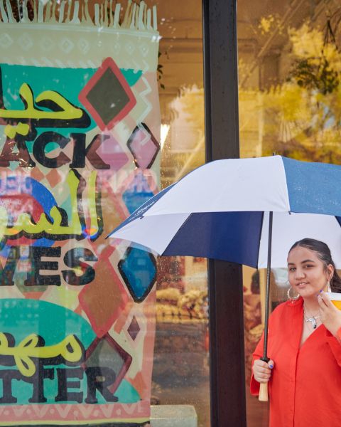 a woman holding an umbrella and coffee cup