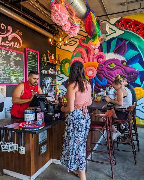 someone orders at a restaurant that is colorfully decorated, people fill the chairs in the background