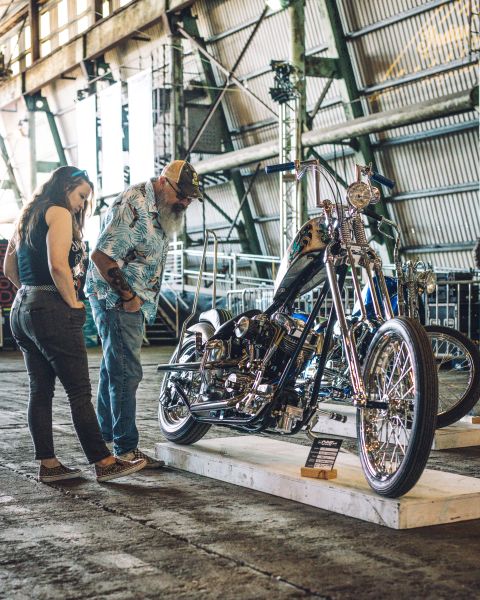 a man and a woman look at a custom motorcycle on display