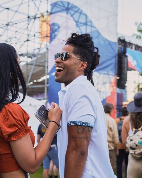 two people laughing with a crowd and stage in the background