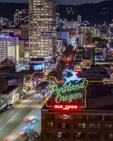 downtown and old town Chinatown are lit up at night behind the Portland stag sign