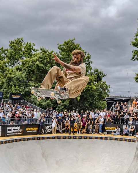 A skateboarder flies through the air while a crowd looks on.