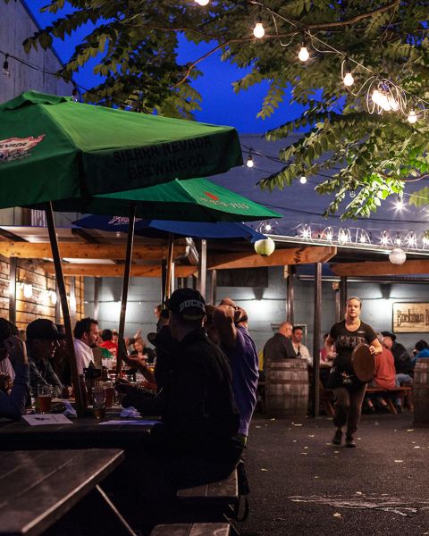 outdoor tables at a pub at night full of customers