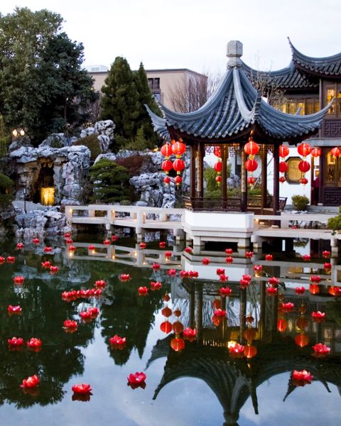 red lanterns float in water in front of a Chinese-style building