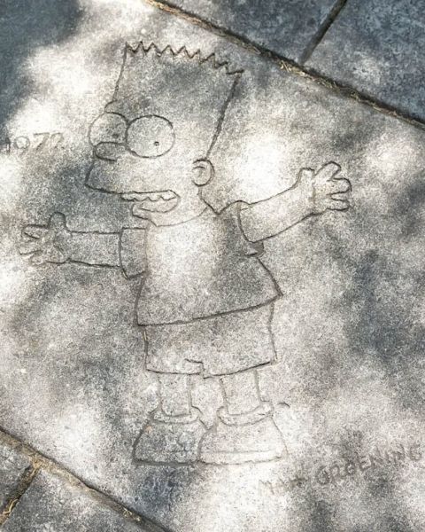 a depiction of cartoon character Bart Simpson on a sidewalk