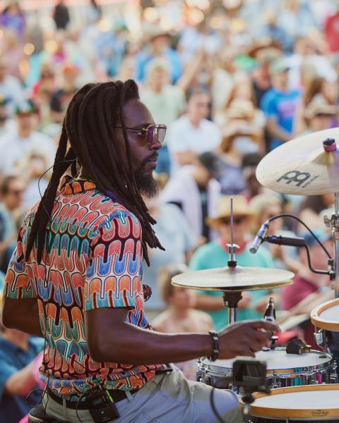 a person sitting at a drum kit in front of a crowd