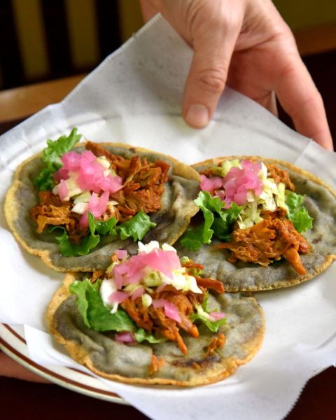 three beautifully made panuchos being held on a plate