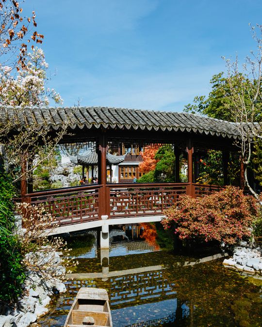 covered bridge crossing a narrow garden stream