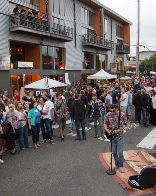crowd gathered around a street musician as he performs at Last Thursday art walk