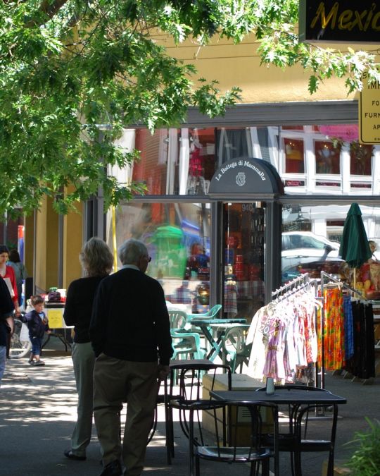 tables and shop items displayed on the sidewalk as people walk by on NW 23rd Avenue