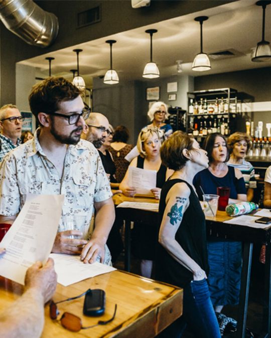 a crowd of people singing together in a bar