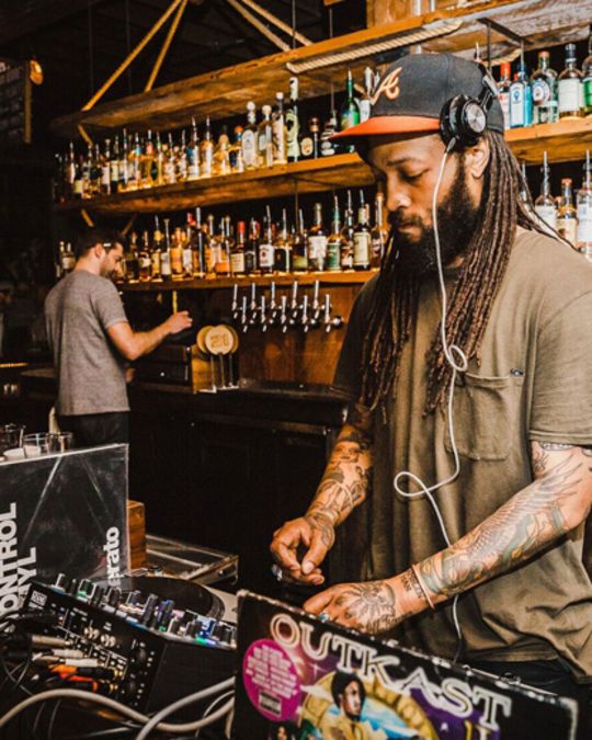 a dj wearing headphones in front of sound equipment plays in a bar