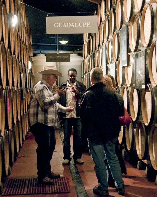 people tasting wine surrounded by wine barrels