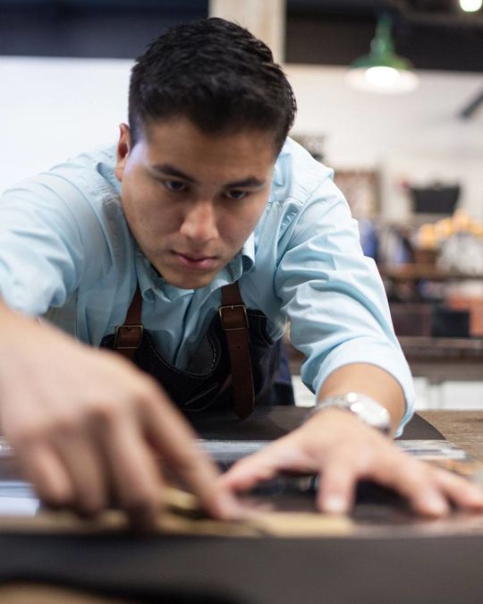 a man at a workbench cutting materials at Orox leather