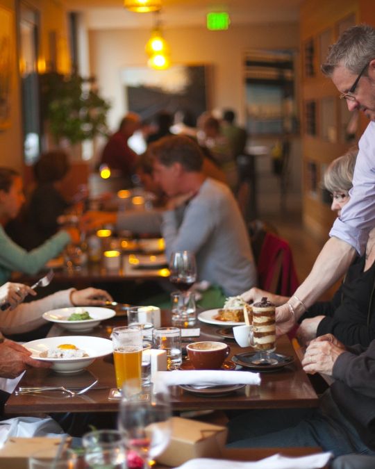 a server giving a table of diners an espresso at a restaurant