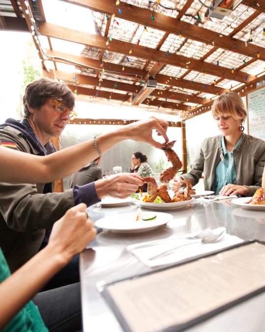 A group of people enjoying fried chicken wings, a favorite at Pok Pok