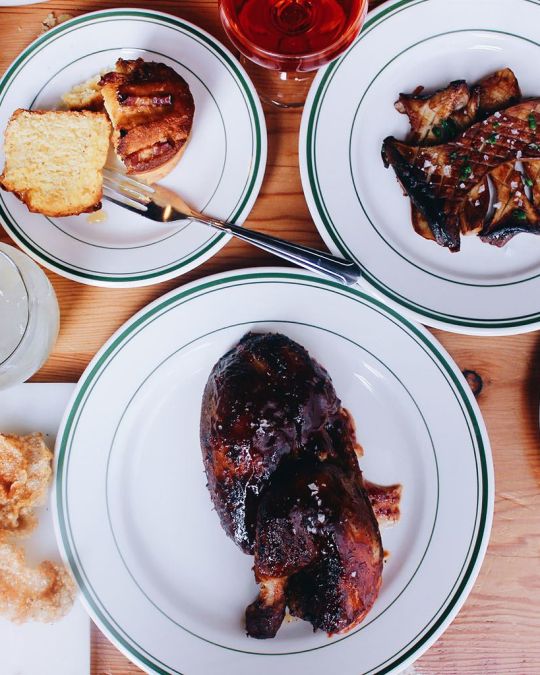 two plates of BBQ and some side dishes