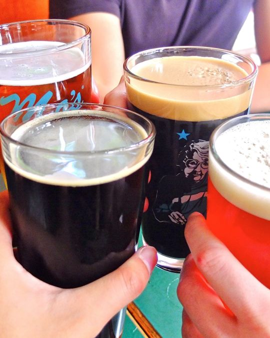 Four hands with four beers toast to world-class beer and spirits at Rogue Distillery and Public House.